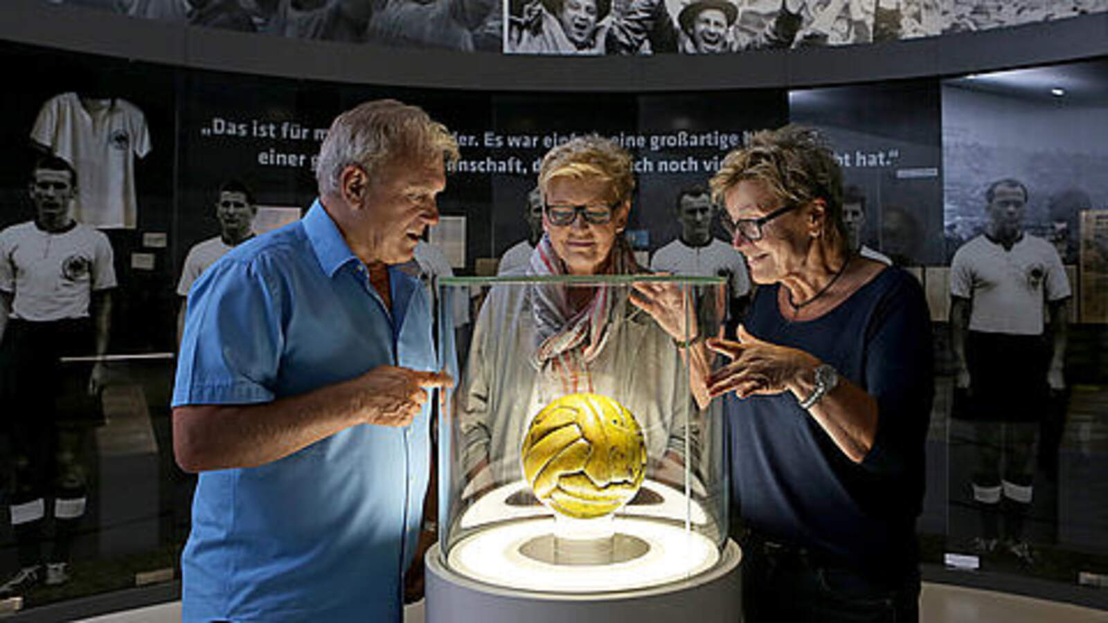 Ältere Herrschaften bestaunen den WM-Ball von 1954
