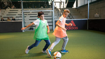 Kinder spielen auf dem Spielfeld in der Arena des Deutschen Fußballmuseums Fußball